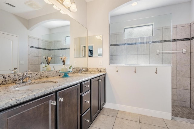 bathroom with a tile shower, vanity, and tile patterned flooring