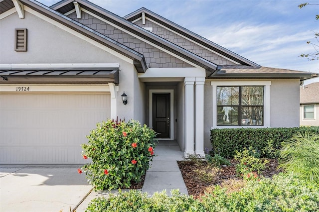 19724 Post Island Loop, Land O Lakes, FL 34638 - view of exterior entry featuring stucco siding, driveway, a garage, and a standing seam roof
