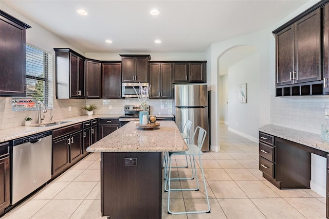 19724 Post Island Loop, Land O Lakes, FL 34638 - kitchen with appliances with stainless steel finishes, a sink, arched walkways, decorative backsplash, and light stone countertops