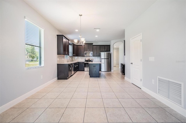 19724 Post Island Loop, Land O Lakes, FL 34638 - kitchen featuring appliances with stainless steel finishes, a chandelier, decorative backsplash, light countertops, and pendant lighting