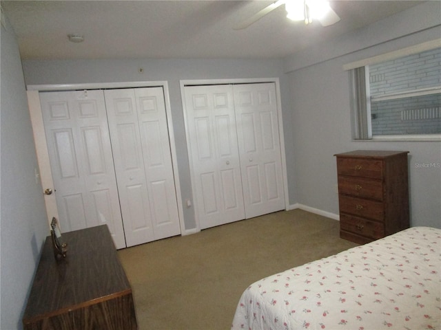 bedroom featuring two closets, ceiling fan, and carpet flooring