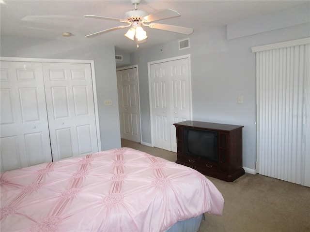 unfurnished bedroom with ceiling fan, light colored carpet, and multiple closets