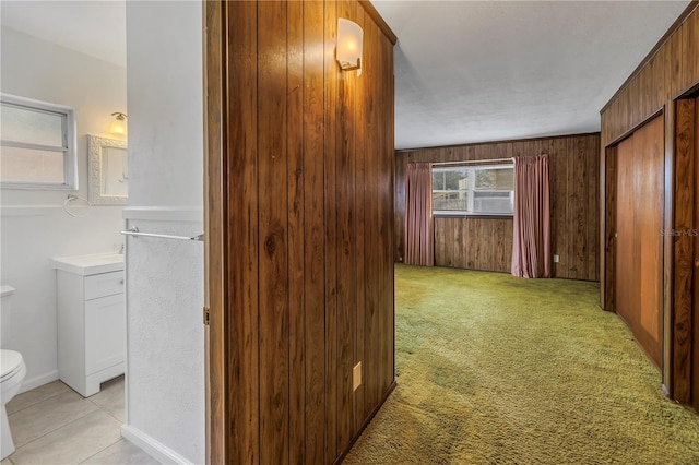 corridor featuring light carpet and wood walls