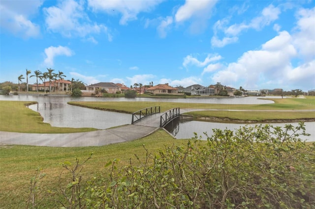 view of home's community with a water view and a lawn