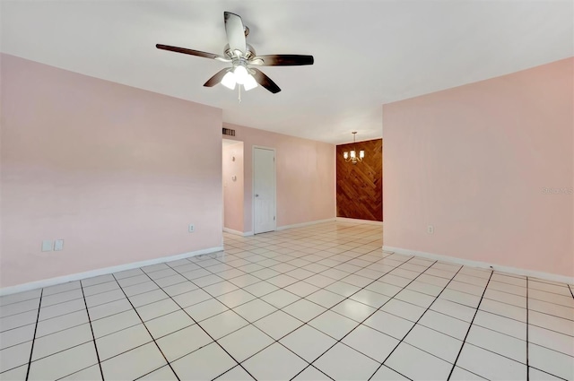 tiled empty room with ceiling fan with notable chandelier and wood walls