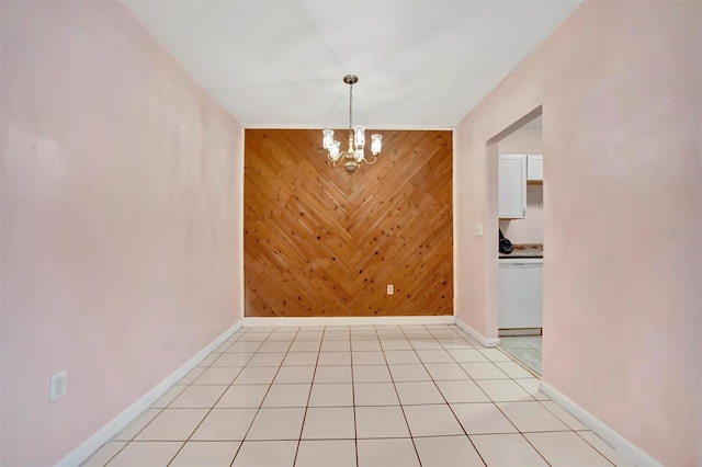 unfurnished dining area featuring a chandelier, light tile patterned floors, and wood walls