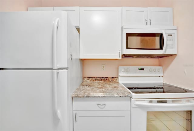 kitchen featuring white appliances, light stone countertops, and white cabinets