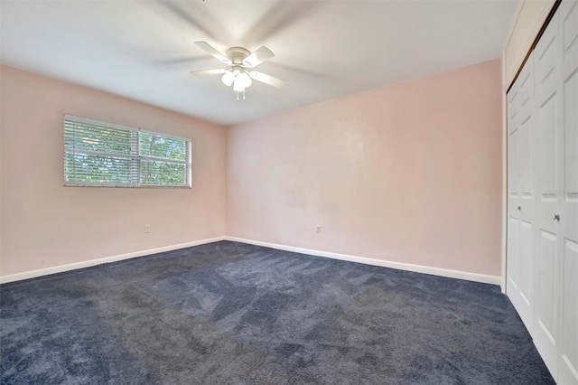 empty room with ceiling fan and dark carpet