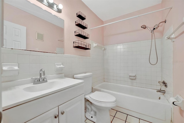 full bathroom with toilet, tiled shower / bath, tile walls, vanity, and tile patterned flooring