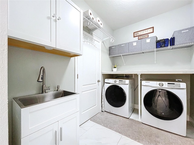 washroom with cabinets, independent washer and dryer, and sink