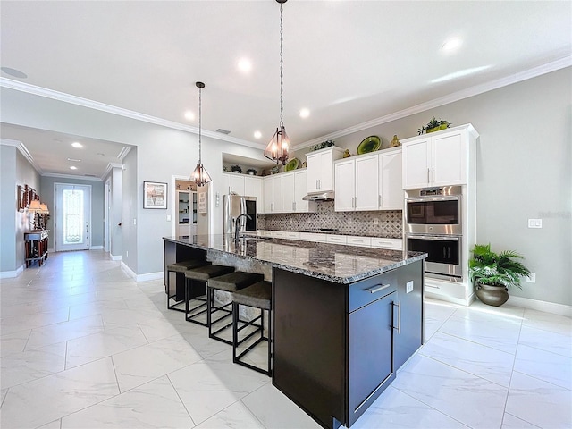 kitchen with white cabinetry, a large island, backsplash, and dark stone counters