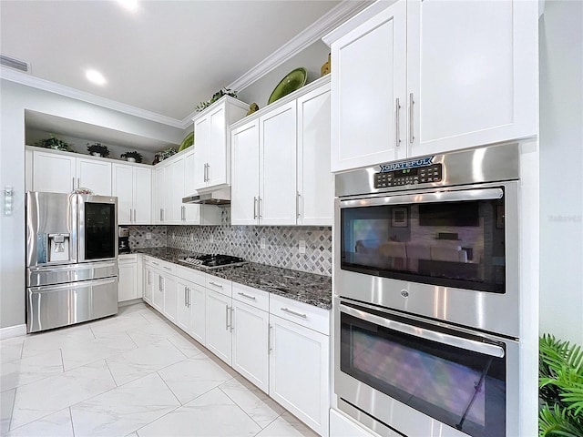 kitchen featuring white cabinetry, stainless steel appliances, crown molding, and dark stone counters