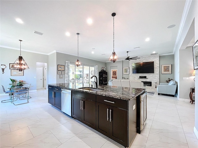 kitchen with sink, decorative light fixtures, stainless steel dishwasher, an island with sink, and dark stone counters