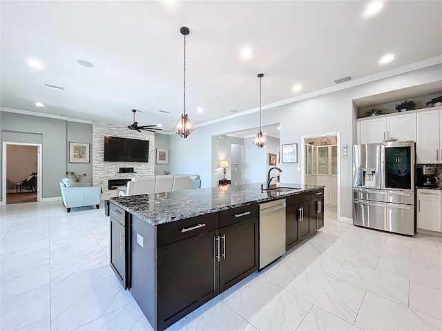 kitchen with white cabinetry, sink, dark stone countertops, hanging light fixtures, and stainless steel appliances