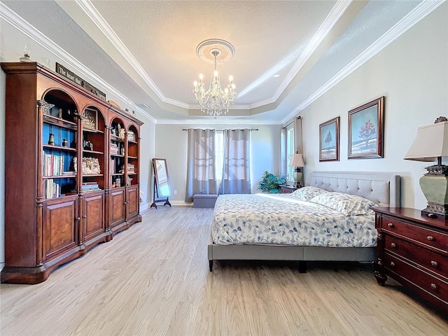 bedroom with crown molding, an inviting chandelier, light hardwood / wood-style floors, and a tray ceiling