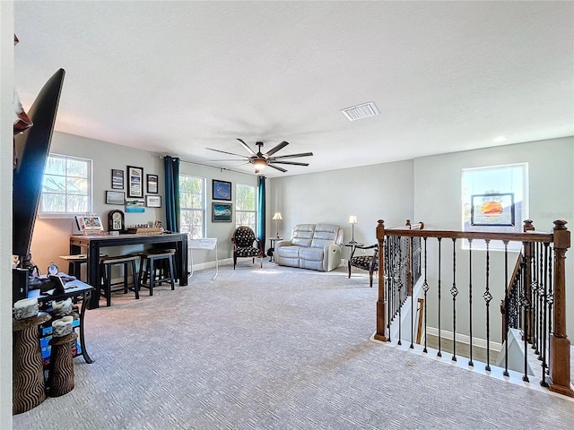 sitting room with ceiling fan, light colored carpet, and a textured ceiling