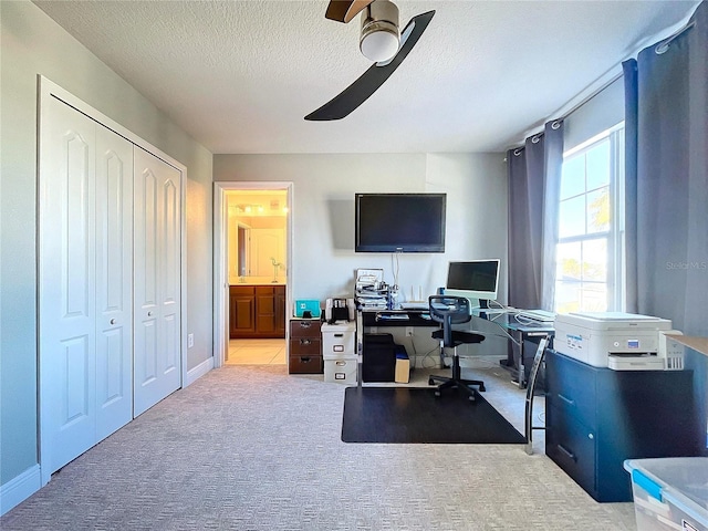 carpeted office space featuring ceiling fan and a textured ceiling