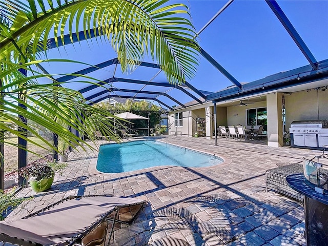 view of pool featuring grilling area, a patio area, ceiling fan, and glass enclosure