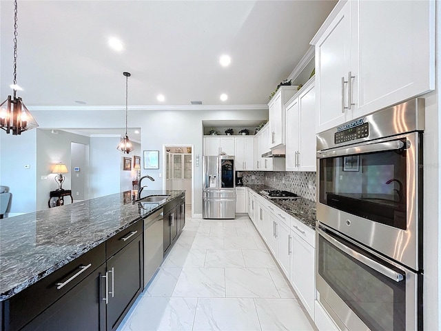 kitchen featuring a spacious island, sink, appliances with stainless steel finishes, pendant lighting, and white cabinets