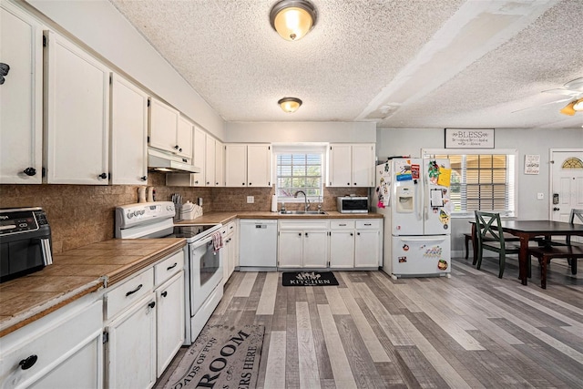 kitchen with sink, white appliances, backsplash, white cabinets, and tile countertops