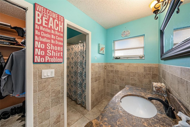 bathroom featuring vanity, tile patterned flooring, a textured ceiling, and tile walls