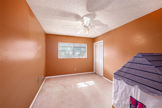 unfurnished bedroom with ceiling fan, carpet floors, a closet, and a textured ceiling