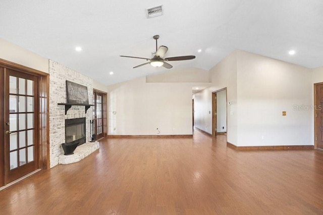 unfurnished living room featuring ceiling fan, lofted ceiling, a stone fireplace, and wood-type flooring