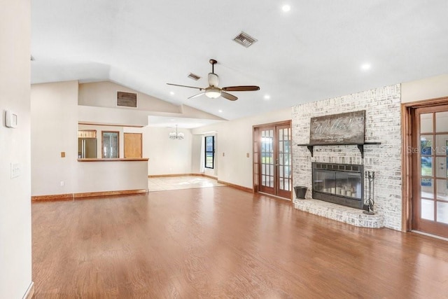 unfurnished living room with french doors, lofted ceiling, wood-type flooring, ceiling fan, and a fireplace