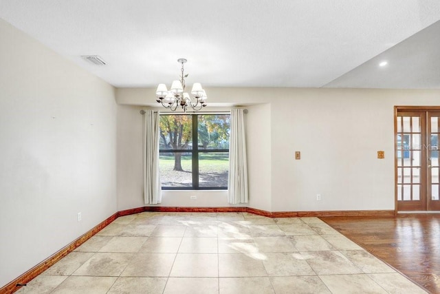 tiled spare room with french doors and a notable chandelier