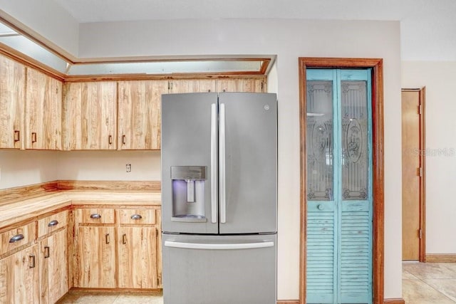 kitchen featuring stainless steel fridge, light brown cabinetry, and light tile patterned floors