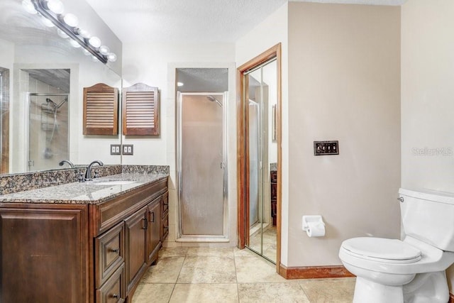 bathroom with tile patterned flooring, vanity, toilet, a shower with door, and a textured ceiling