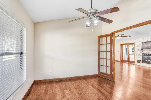 spare room with hardwood / wood-style floors, a fireplace, french doors, and ceiling fan