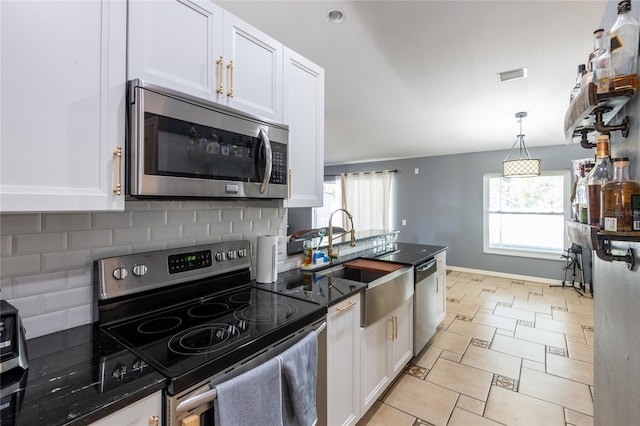 kitchen with sink, tasteful backsplash, hanging light fixtures, appliances with stainless steel finishes, and white cabinets