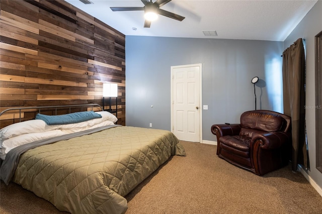 carpeted bedroom featuring ceiling fan and wood walls