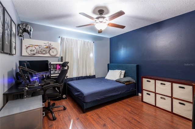 bedroom featuring dark hardwood / wood-style flooring, ceiling fan, and a textured ceiling