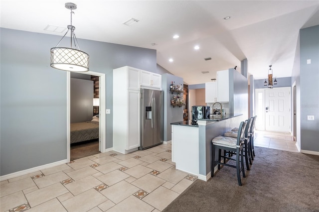 kitchen featuring stainless steel refrigerator with ice dispenser, lofted ceiling, white cabinetry, decorative light fixtures, and kitchen peninsula