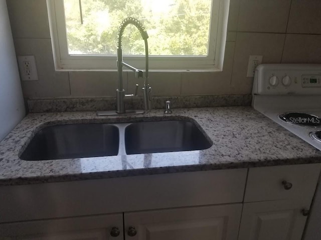 interior space with white cabinetry, sink, and light stone countertops