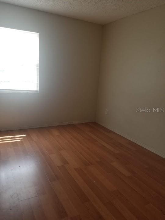 spare room featuring wood-type flooring and a textured ceiling