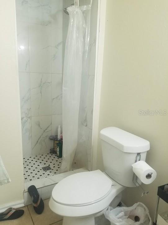 bathroom with walk in shower, tile patterned floors, and toilet