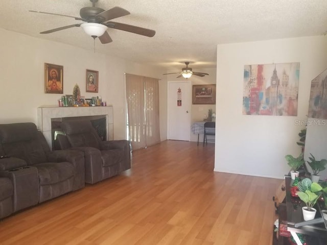 living room featuring hardwood / wood-style flooring, ceiling fan, and a textured ceiling