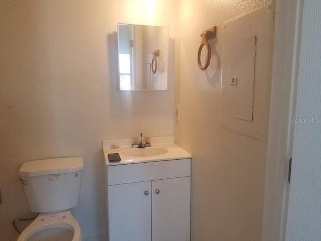 bathroom featuring vanity, electric panel, and toilet