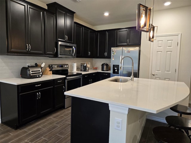 kitchen with a breakfast bar, tasteful backsplash, sink, stainless steel appliances, and a center island with sink