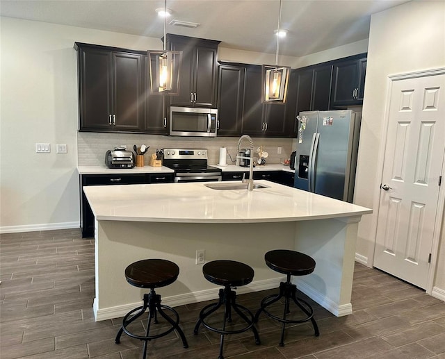 2878 Grand Kemerton Pl, Tampa, FL 33618 - kitchen featuring sink, appliances with stainless steel finishes, a kitchen breakfast bar, pendant lighting, and a kitchen island with sink