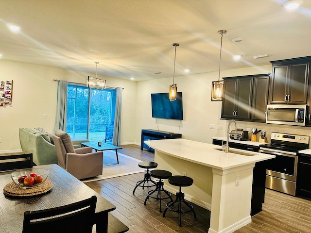 2878 Grand Kemerton Pl, Tampa, FL 33618 - kitchen featuring pendant lighting, an island with sink, a kitchen breakfast bar, decorative backsplash, and stainless steel appliances