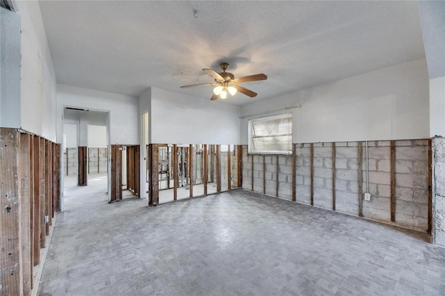 empty room with ceiling fan and a textured ceiling