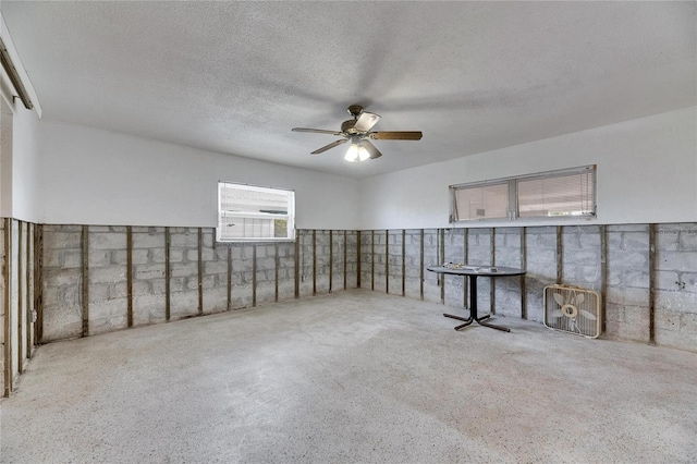 basement with ceiling fan and a textured ceiling