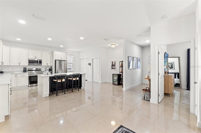 kitchen featuring white cabinetry, stainless steel appliances, a breakfast bar, and a kitchen island