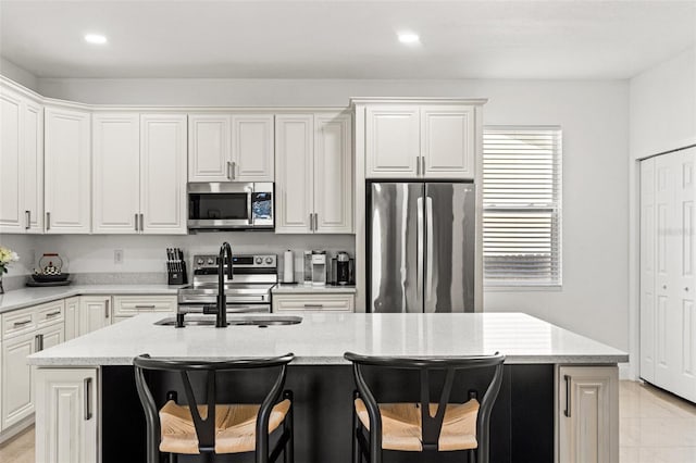 kitchen featuring white cabinetry, sink, stainless steel appliances, and a center island with sink