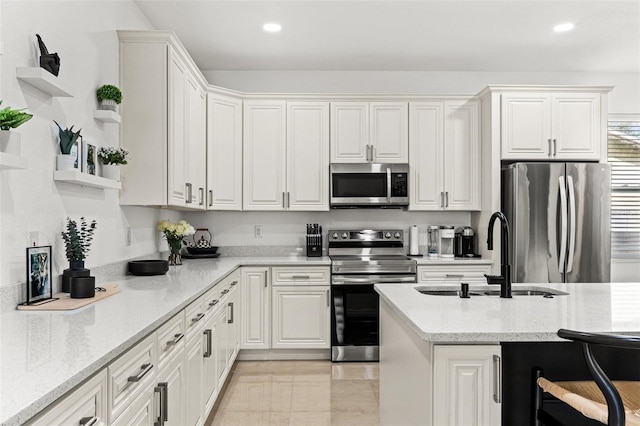 kitchen with stainless steel appliances, sink, white cabinets, and light stone counters