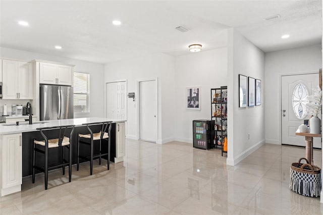 kitchen featuring sink, a breakfast bar area, white cabinets, and appliances with stainless steel finishes